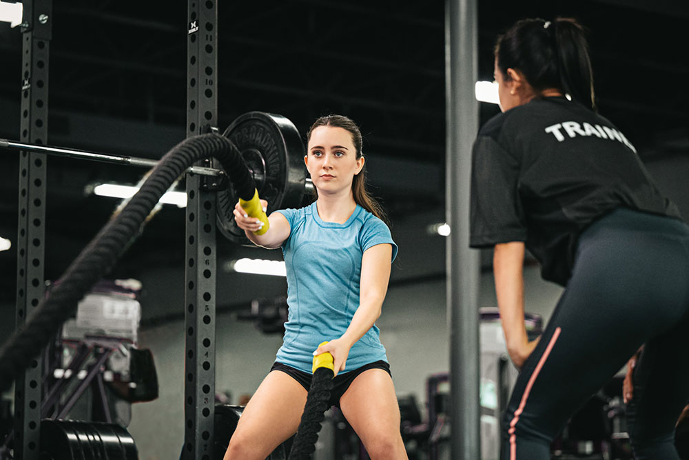 trainer watches an intent woman doing the Olympic ropes