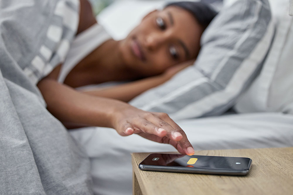 a woman sets her phone alarm before sleeping